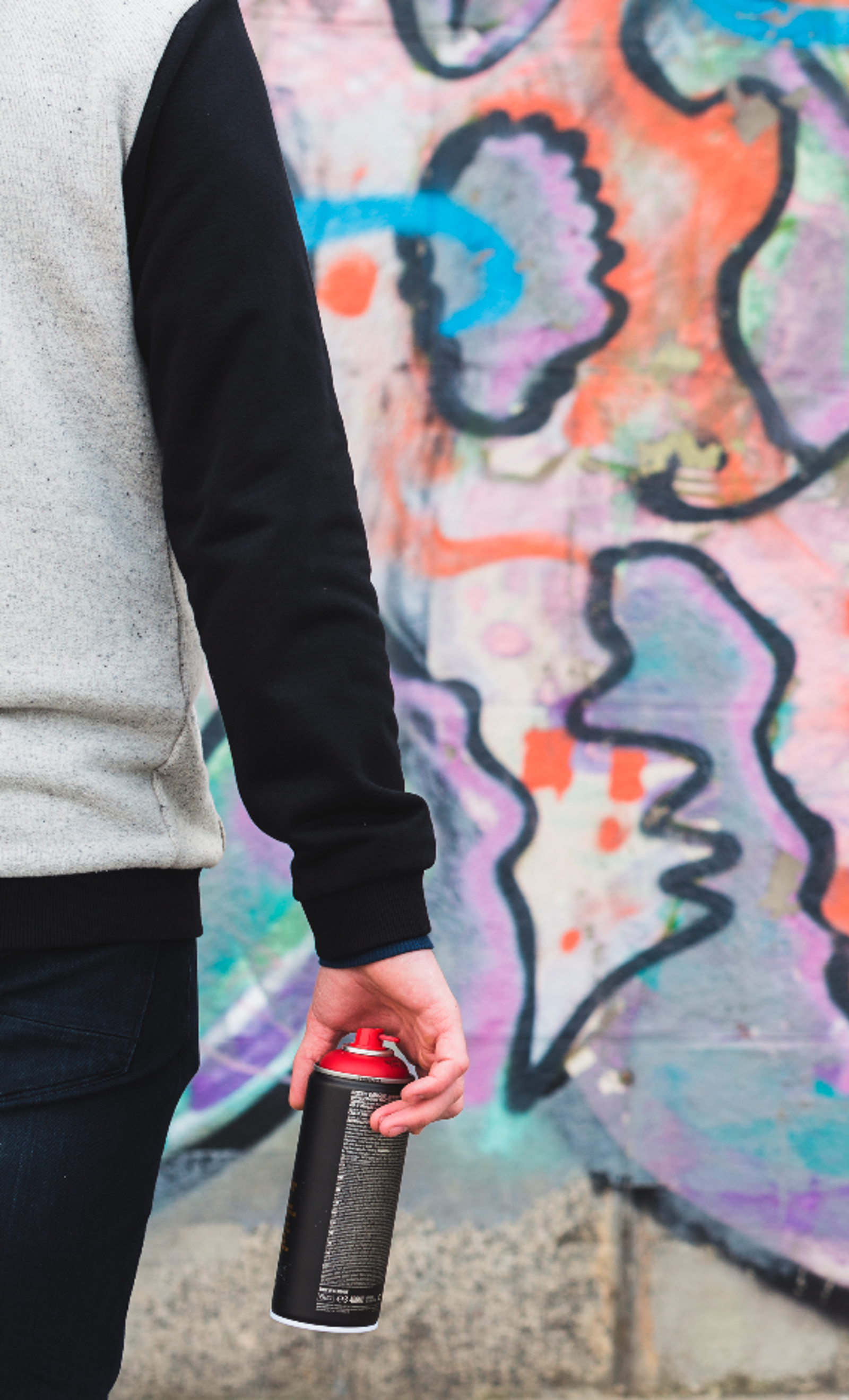 Person standing with spray can looking at graffiti